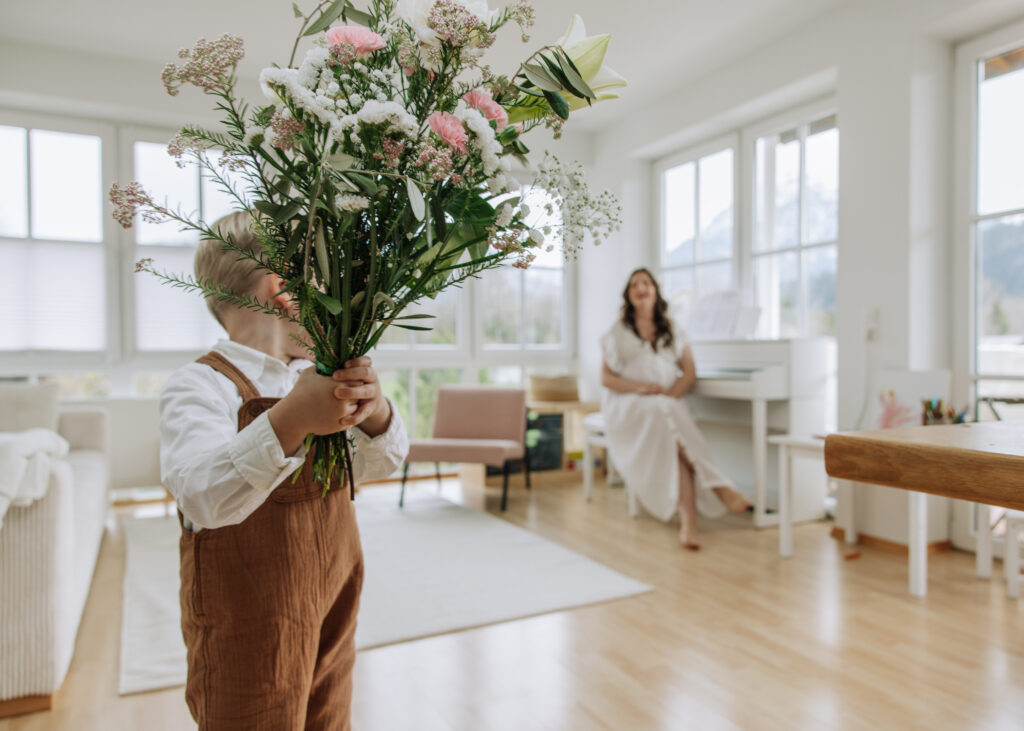 Blumenstrauß in den Händen von jungem Sohn der zu seiner Mutter schaut