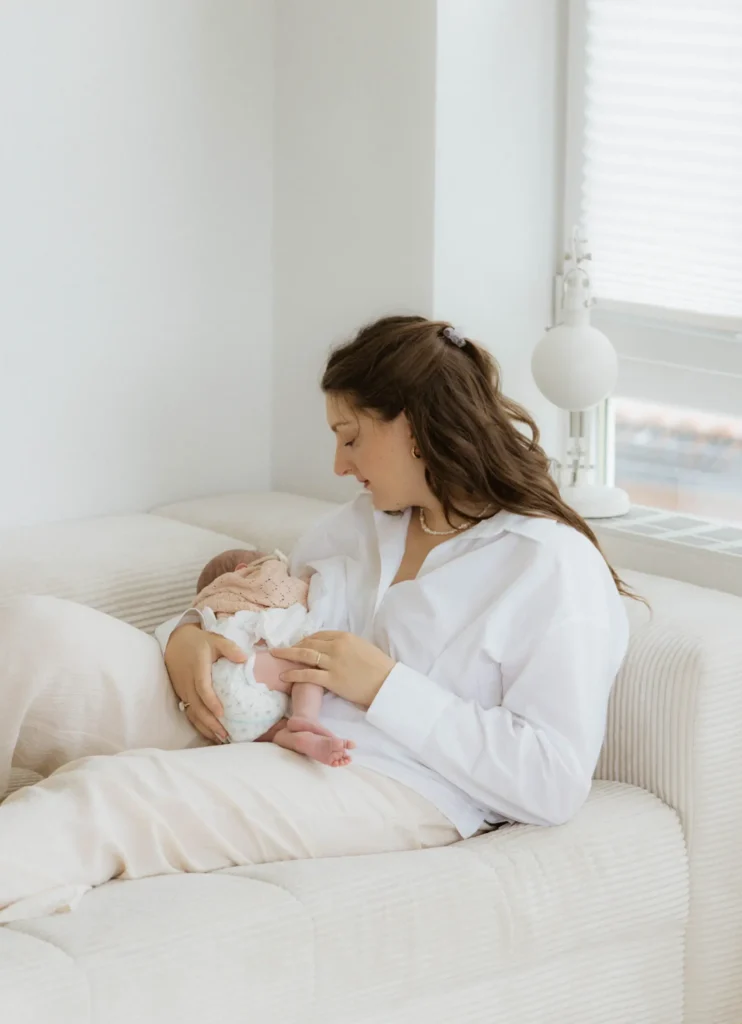 Mutter stillt ihre kleine neugeborene Tochter beim Baby Shooting in Füssen