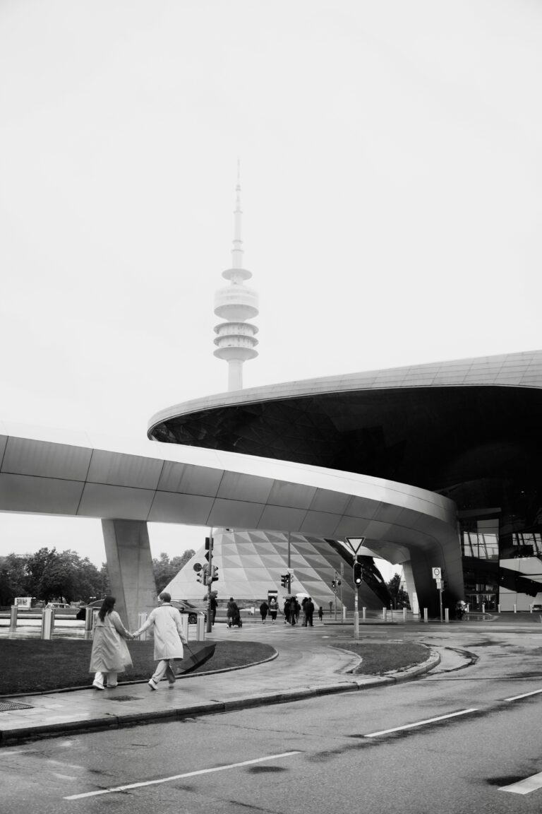 Pärchen läuft beim Paarfotoshooting München Hand in Hand Richtung BMW Welt München.