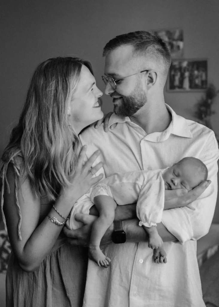 Junges glückliches Ehepaar mit Neugeborenem in den Händen des Vaters