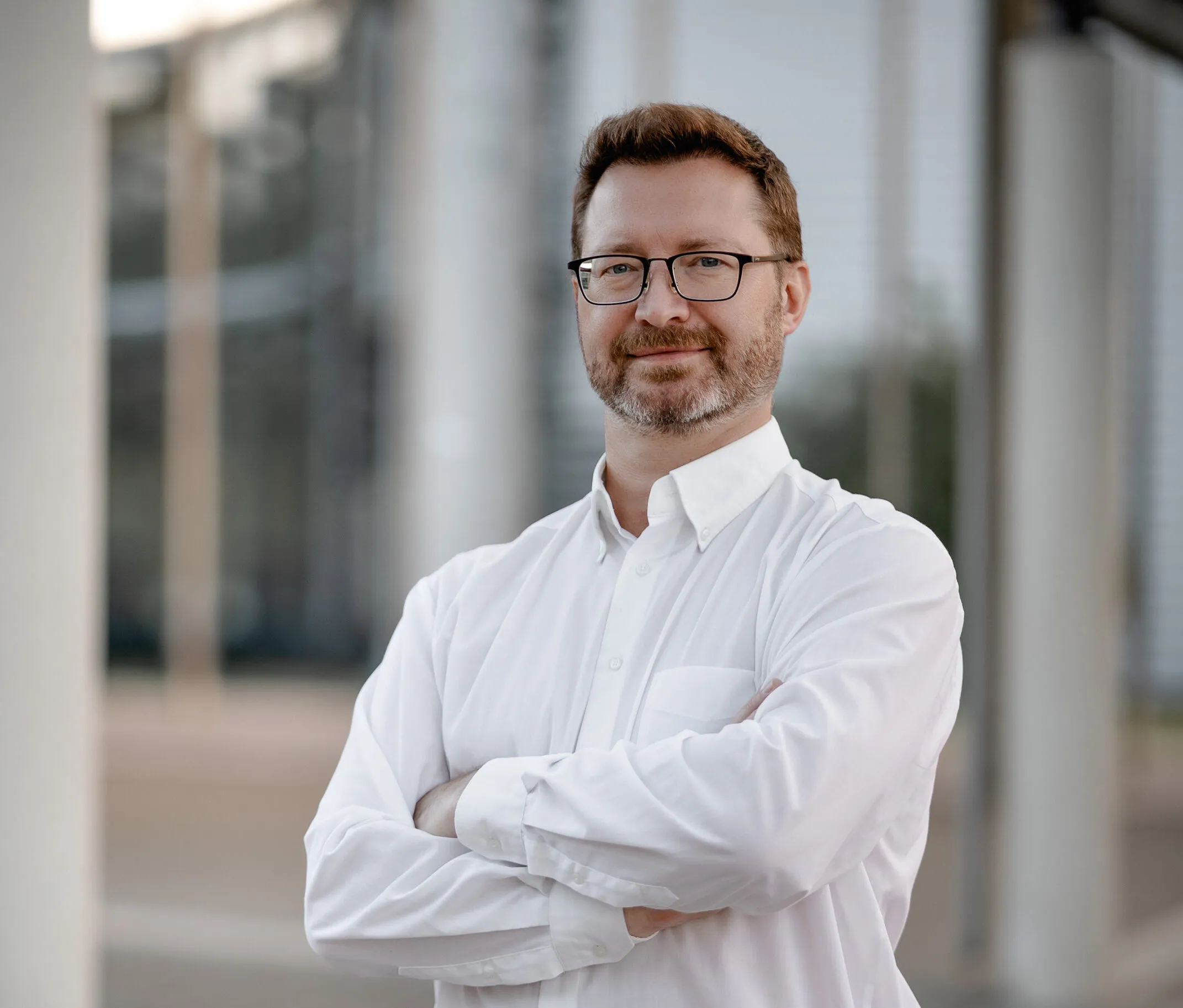 Mann in Hemd vor einem Unternehmensgebäude München