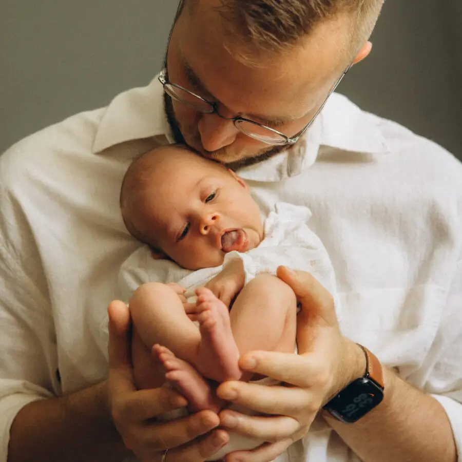 Vater küsst sein Neugeborenes beim Babyshooting München