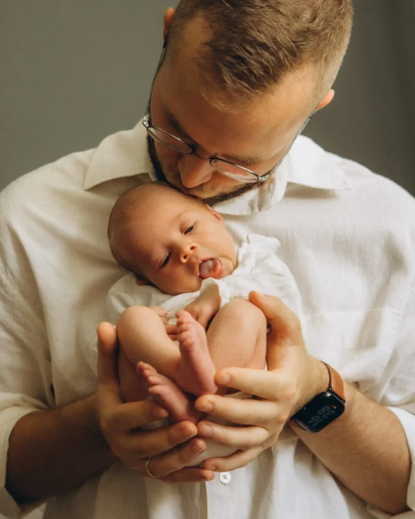 Vater küsst sein Neugeborenes beim Babyshooting München