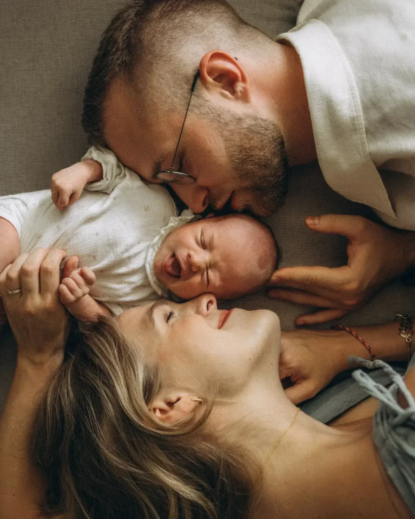 Junge Familie liegt kuschelnd auf der Couch