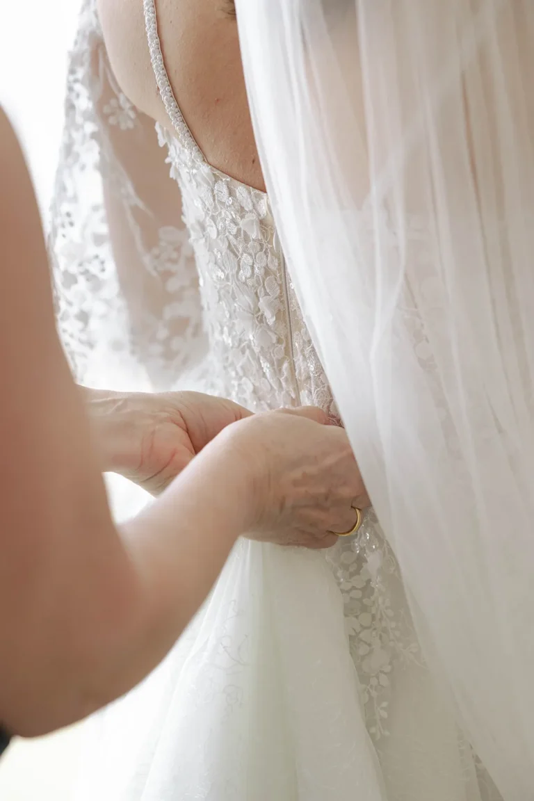 Eine Hand richtet das Hochzeitskleid der Braut