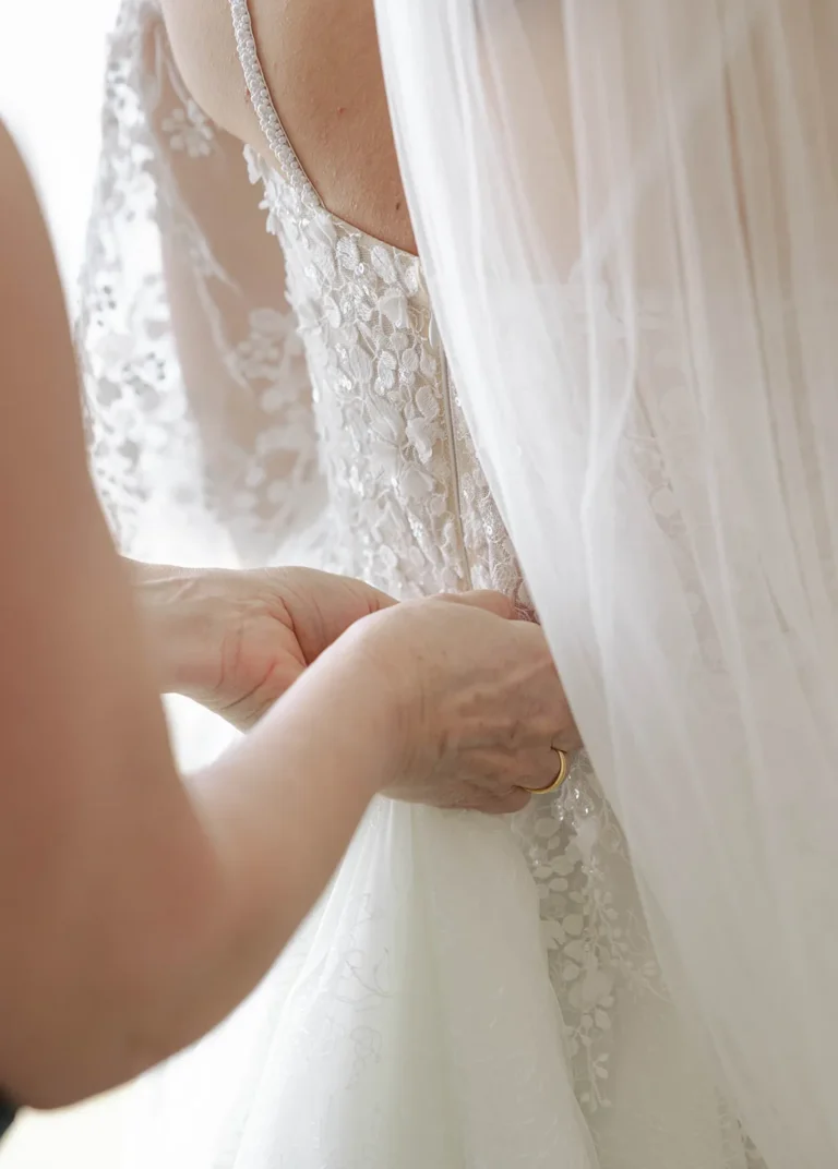 Eine Hand richtet das Hochzeitskleid der Braut