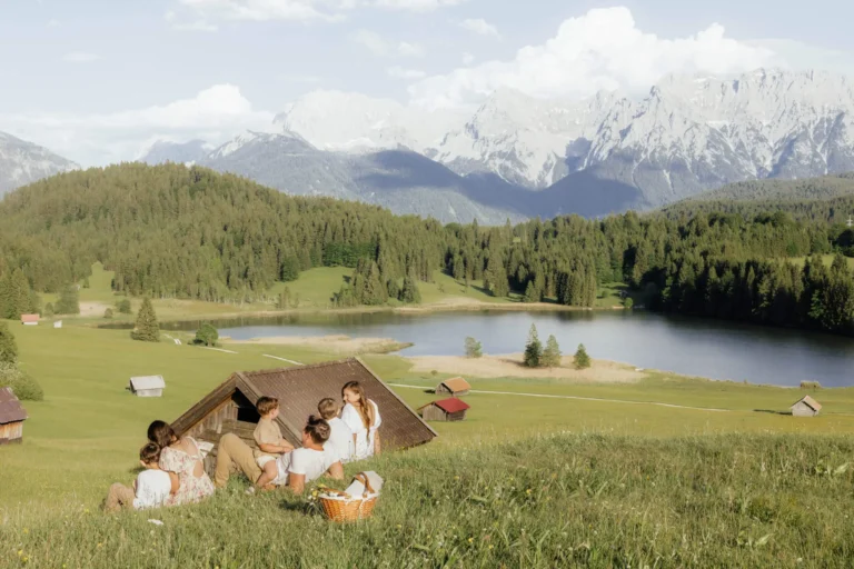 Familie sitzt vor einer schönen Berglandschaft in Bayern am Familienfotoshooting München