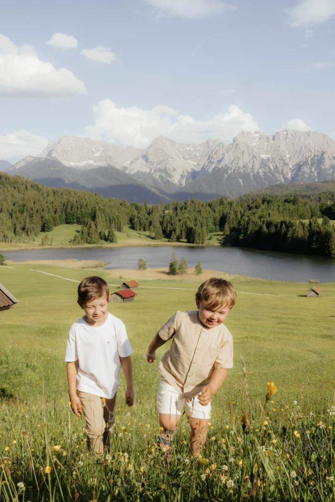 Zwei kleine Junge rennen über die Wiese beim Familienfotoshooting Bayern in den Bergen
