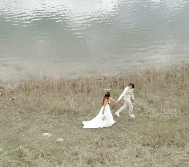 Hochzeitsfotograf München: Brautpaar läuft Hand in Hand am See entlang